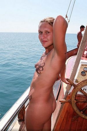 Большая группа голых нудистов отдыхают катаясь на яхте